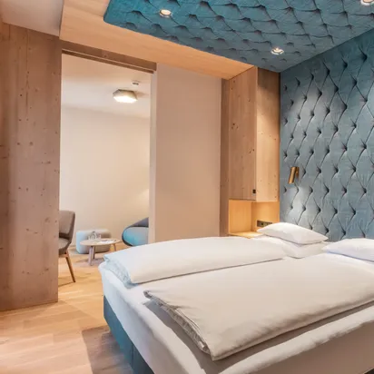 Modern hotel room with double bed, wood accents, and padded blue wall design